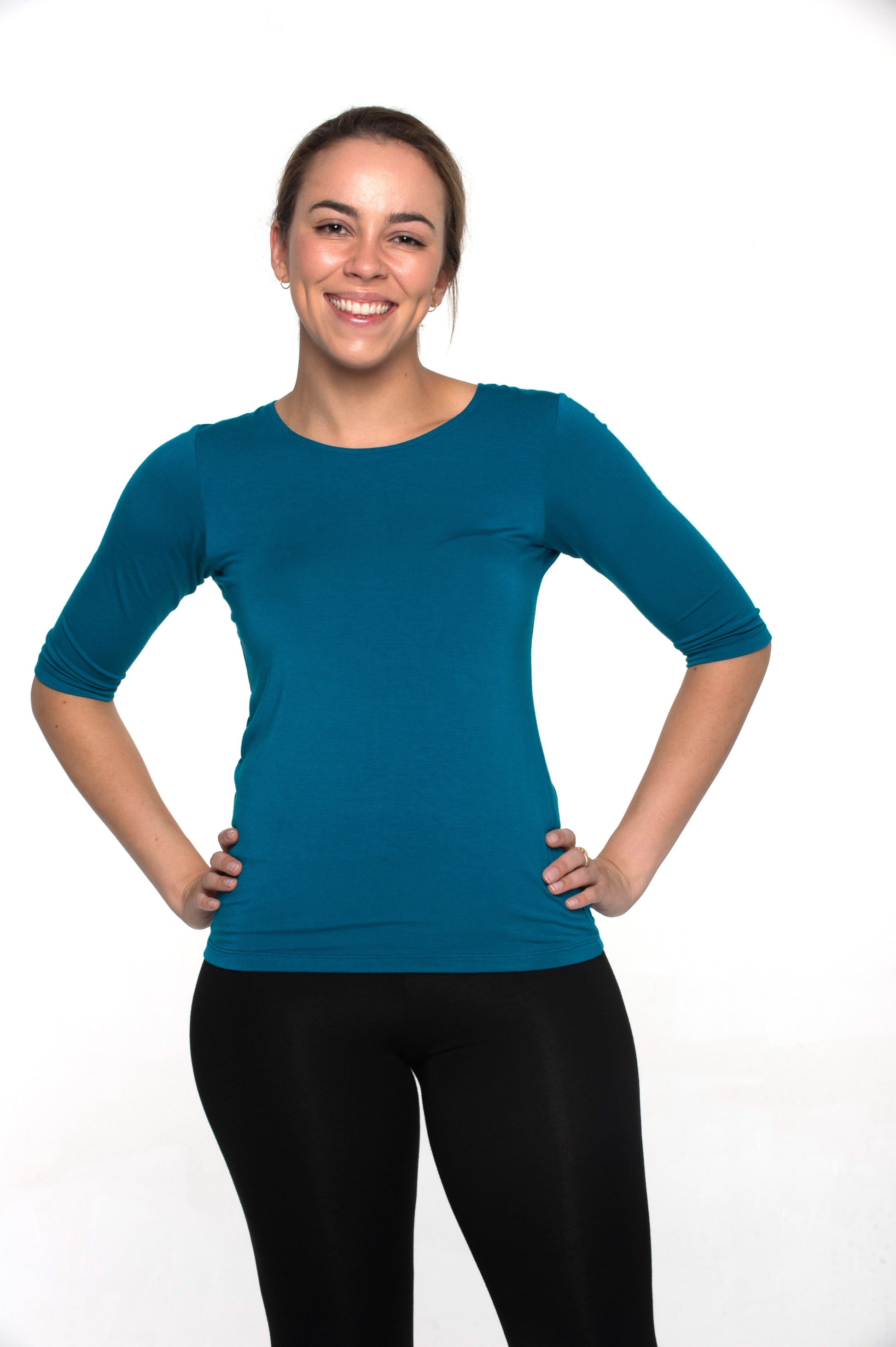 A woman wearing a blue, 3/4 sleeve top with a round neckline, in a relaxed fit.